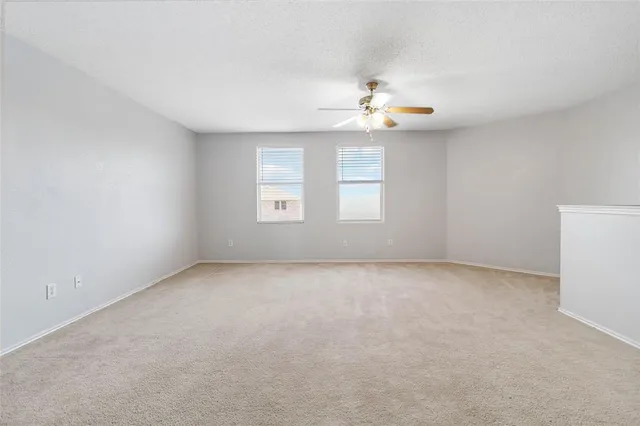 an empty room with windows and chandelier fan