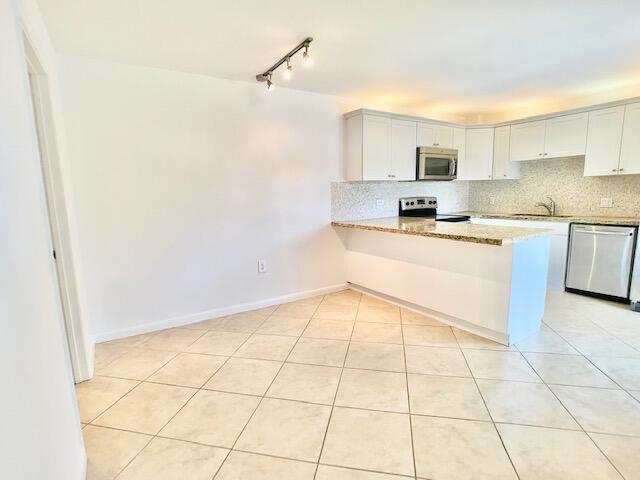 3900 County Line Road, Unit 2D Tequesta, FL 33469 - Photo 5 of 19 a kitchen with stainless steel appliances cabinets a sink and a counter top space
