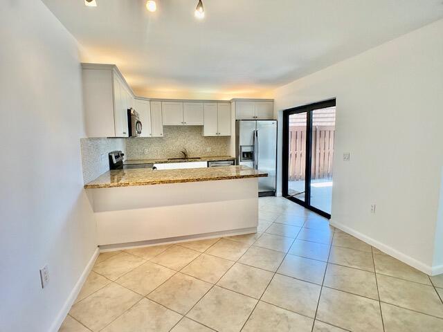 3900 County Line Road, Unit 2D Tequesta, FL 33469 - Photo 6 of 19 a large white kitchen with a sink and a large mirror next to a window