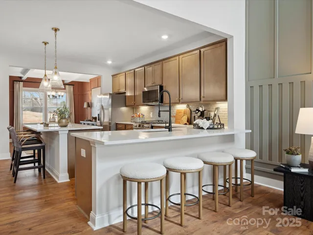 a kitchen with stainless steel appliances kitchen island granite countertop a table chairs and a refrigerator