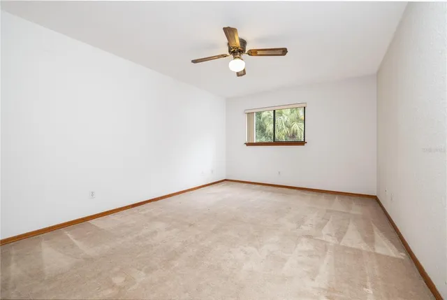 an empty room with window and ceiling fan