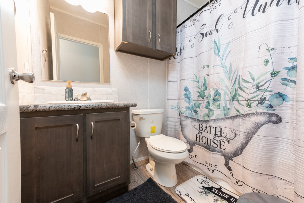 859 Ivy Switch Road Luling, TX 78648 - Photo 21 of 29 Bathroom featuring vanity, wood finished floors, a shower with curtain, and ornamental molding