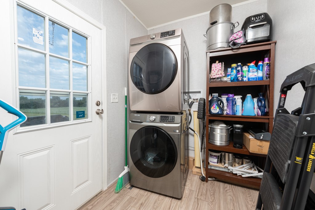 859 Ivy Switch Road Luling, TX 78648 - Photo 23 of 29 Washroom featuring stacked washing machine and dryer, light wood-style flooring, and ornamental molding