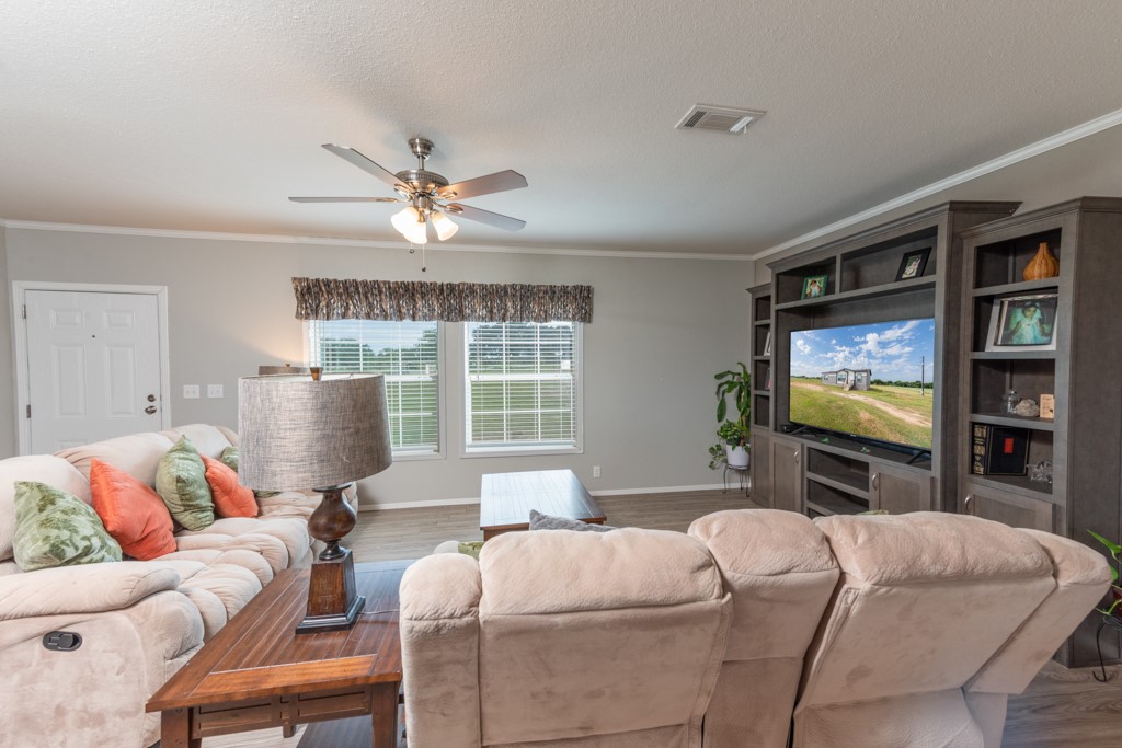 859 Ivy Switch Road Luling, TX 78648 - Photo 10 of 29 Living room featuring ornamental molding, wood finished floors, ceiling fan, and a textured ceiling