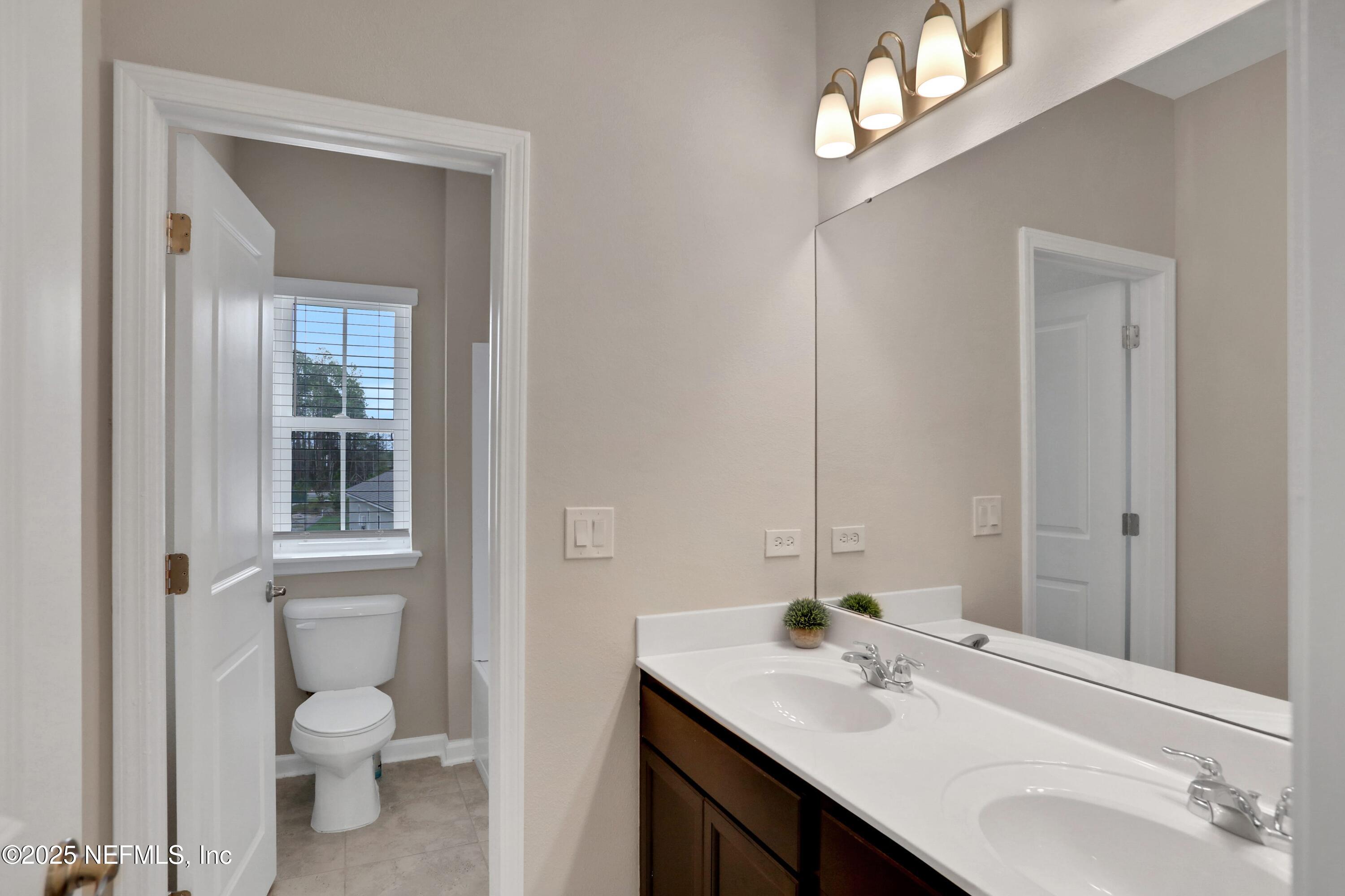 494 Archstone Way St. Augustine, FL 32092 - Photo 65 of 67 a bathroom with a toilet a sink a mirror and a window