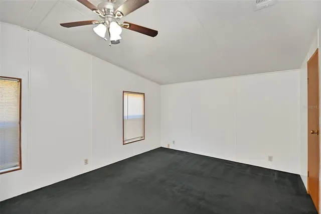 an empty room with windows and fan