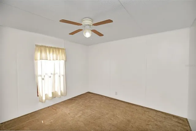 an empty room with a ceiling fan and a window