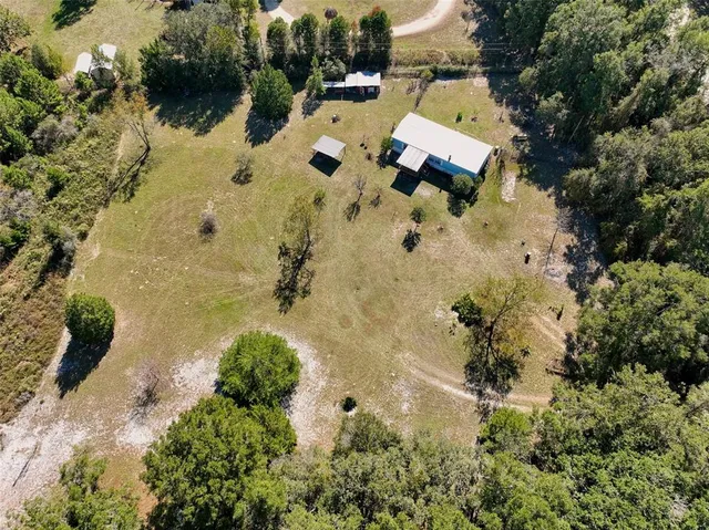 an aerial view of residential house with yard and outdoor seating