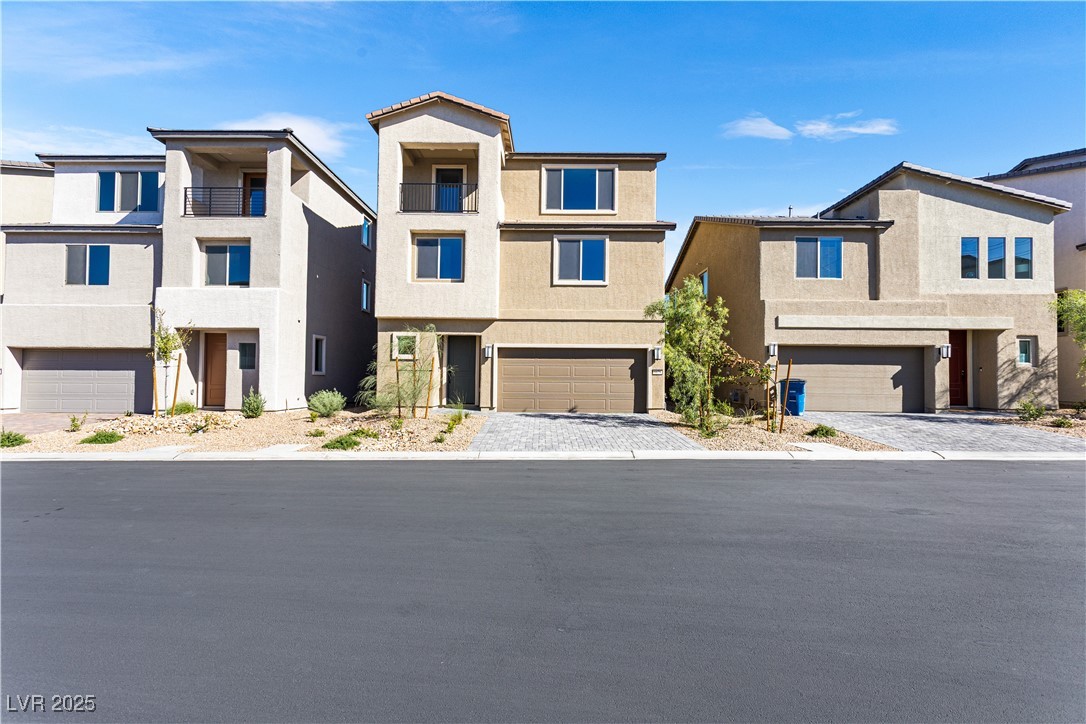 5678 Spring Trellis Street Las Vegas, NV 89113 - Photo 16 of 22 View of front of property featuring stucco siding, a balcony, decorative driveway, and an attached garage