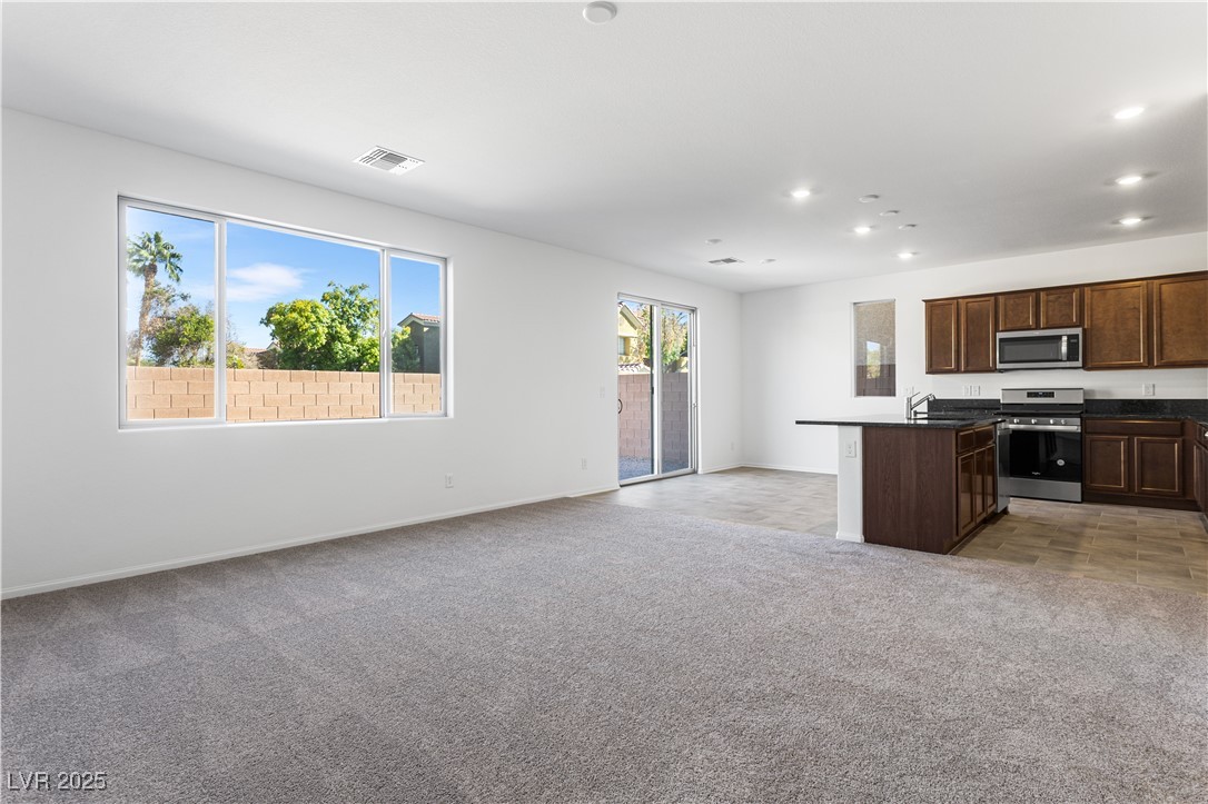 5678 Spring Trellis Street Las Vegas, NV 89113 - Photo 22 of 22 Kitchen with open floor plan, stainless steel appliances, dark brown cabinetry, a kitchen island with sink, and light colored carpet