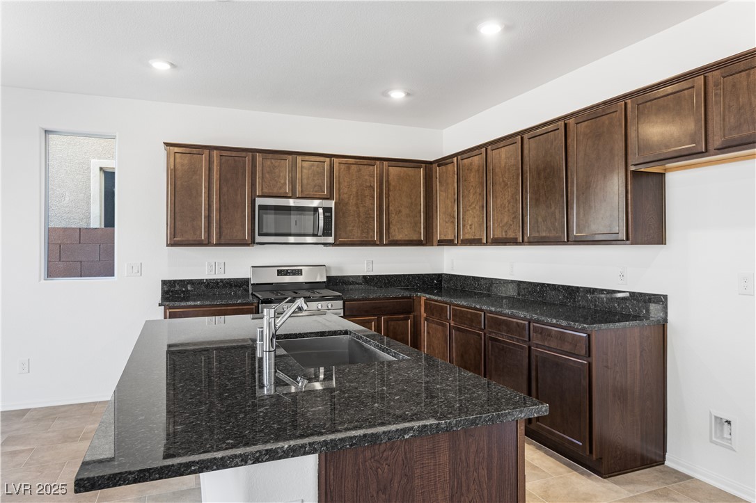 5678 Spring Trellis Street Las Vegas, NV 89113 - Photo 4 of 22 Kitchen featuring dark stone countertops, dark brown cabinetry, appliances with stainless steel finishes, and recessed lighting