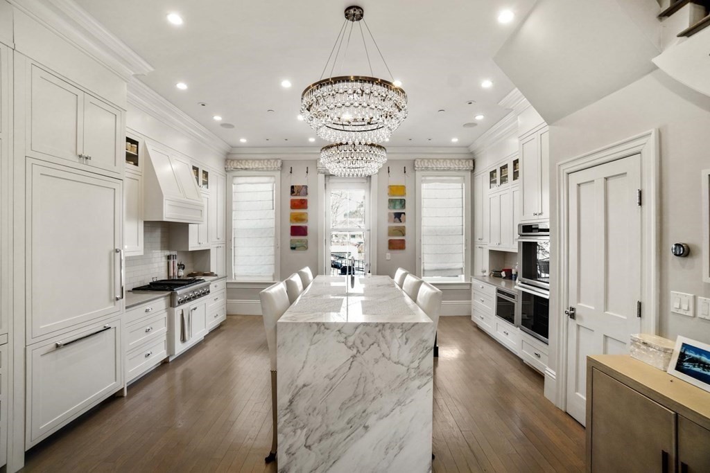 a large kitchen with granite countertop a large center island a sink stainless steel appliances and cabinets