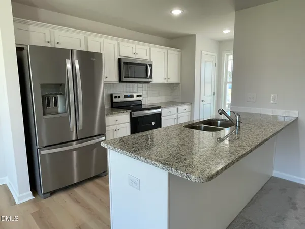 a kitchen with stainless steel appliances granite countertop a kitchen island a refrigerator a stove a sink and a granite counter tops