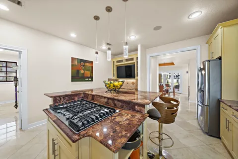a kitchen with stainless steel appliances granite countertop a stove refrigerator and chairs