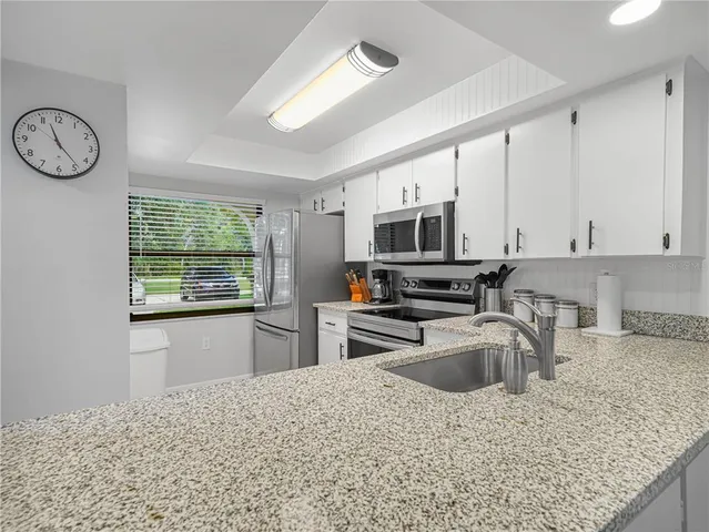 a kitchen with stainless steel appliances granite countertop a sink stove and microwave