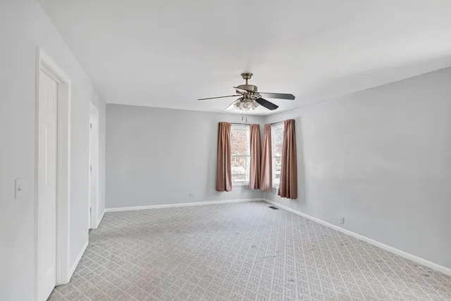 a view of an empty room with chandelier fan