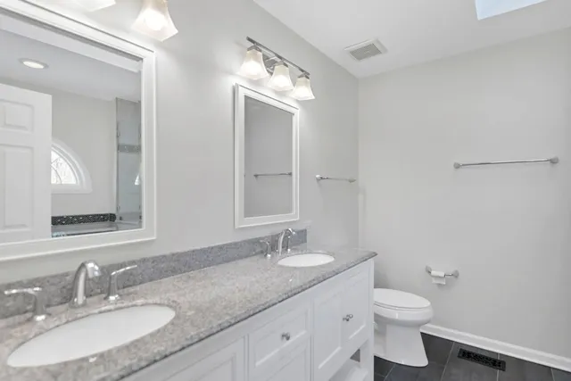 a bathroom with a granite countertop sink a toilet and a mirror