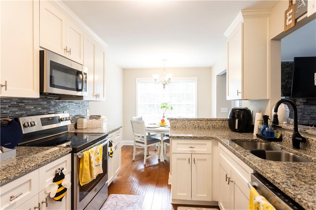355 Conner Court Social Circle, GA 30025 - Photo 12 of 52 a kitchen with stainless steel appliances granite countertop a stove top oven a sink a dining table and chairs