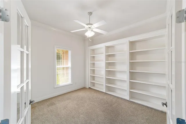 an empty room with a ceiling fan and window