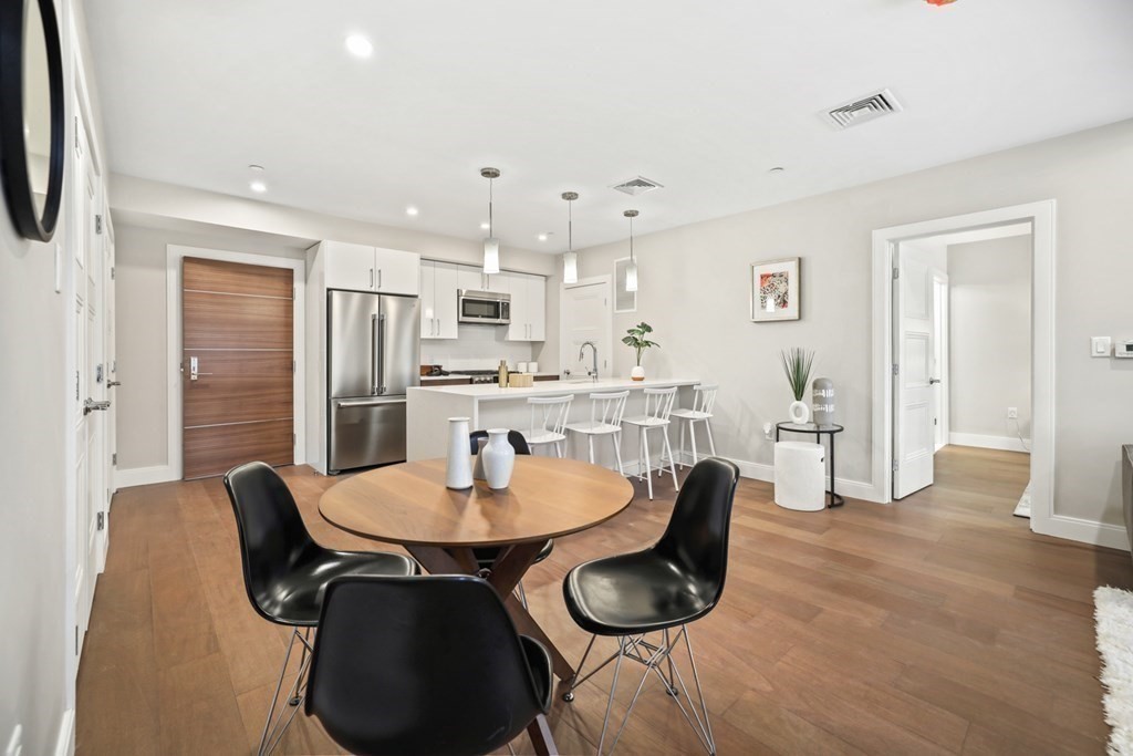 a kitchen with stainless steel appliances granite countertop a dining table chairs and a refrigerator