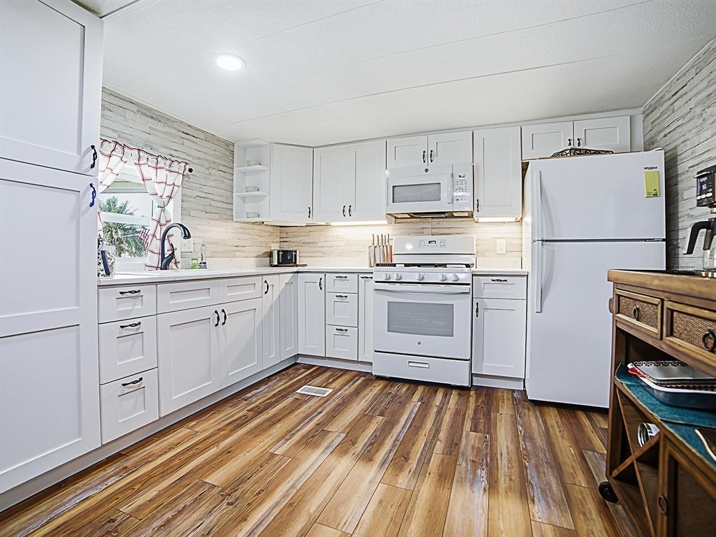 211 Rue De Paresse Tavares, FL 32778 - Photo 4 of 27 a kitchen with white cabinets and white appliances