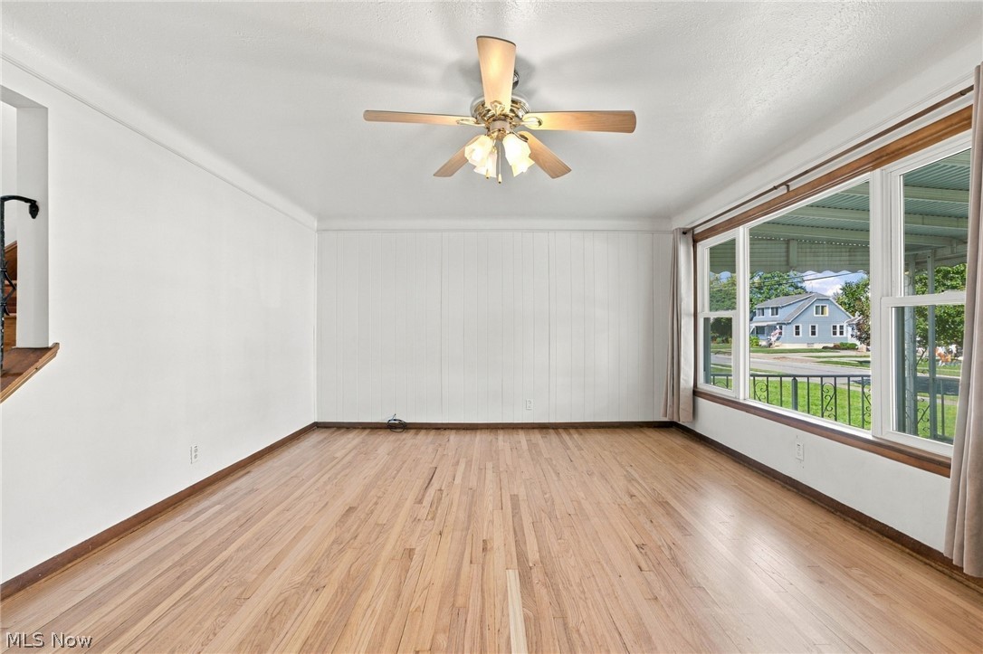 1434 Sunset Road Mayfield Heights, OH 44124 - Photo 17 of 36 Wood-finish flooring, white paneled wall, large picture windows, and a ceiling fan