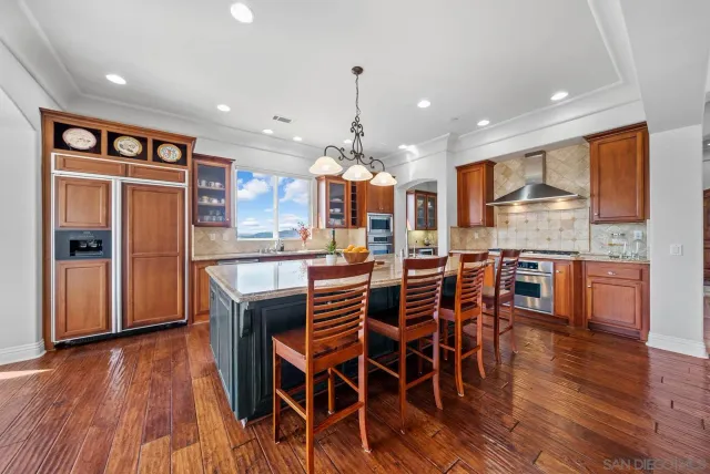 an open kitchen with wooden floor and stainless steel appliances