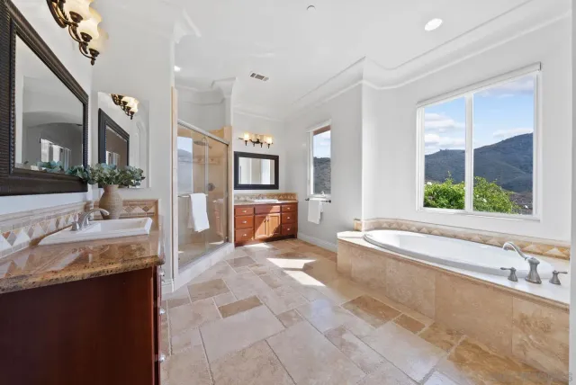 a large bathroom with a tub a sink and a large mirror