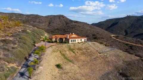 a front view of a house with a yard and mountain view in back