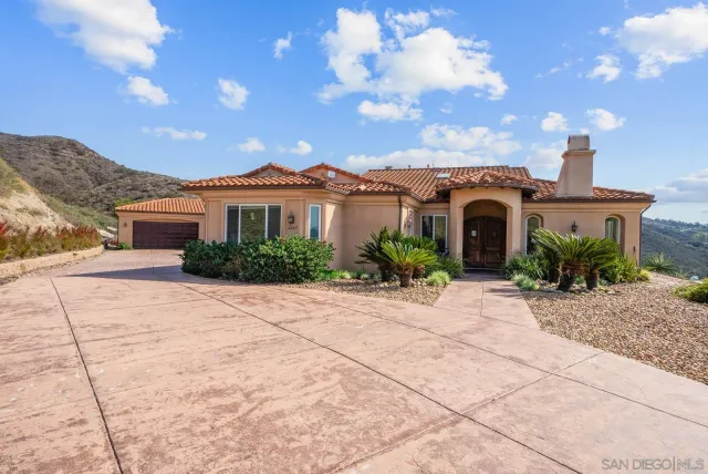 a front view of a house with a yard and mountain view in back