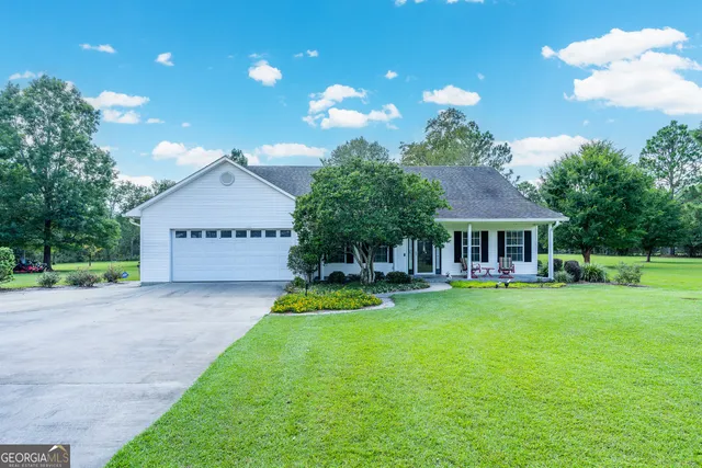 a view of a house with a yard potted plants and a bench