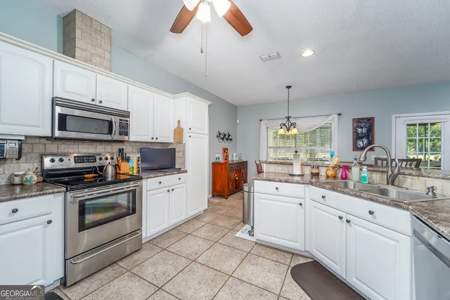 a kitchen with stainless steel appliances granite countertop a sink a stove and cabinets