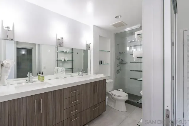 a bathroom with a double vanity sink toilet mirror and shower