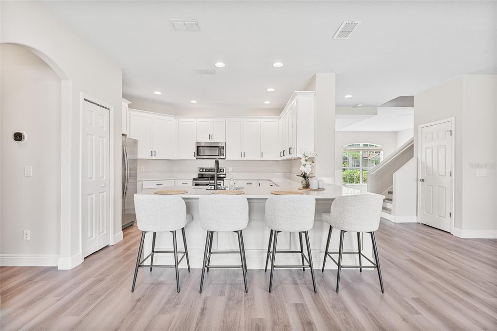 3333 Atmore Terrace Ocoee, FL 34761 - Photo 4 of 37 a kitchen with stainless steel appliances granite countertop a dining table chairs wooden floors and white cabinets