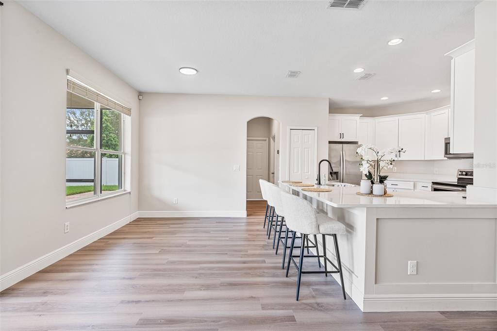3333 Atmore Terrace Ocoee, FL 34761 - Photo 6 of 37 a kitchen with stainless steel appliances a sink a stove a refrigerator cabinets and a dining table with wooden floor
