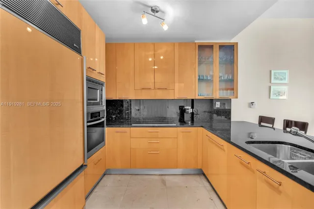a kitchen with stainless steel appliances granite countertop a table chairs and a refrigerator