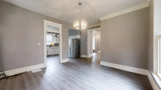 a view of a hallway with wooden floor and a kitchen