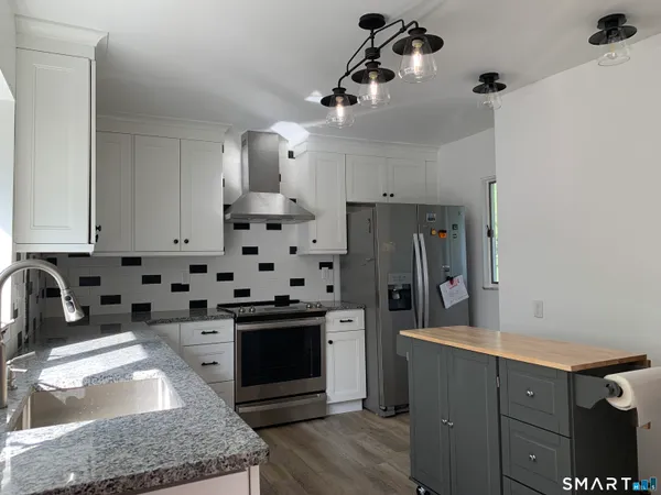 a kitchen with granite countertop a sink a stove and refrigerator