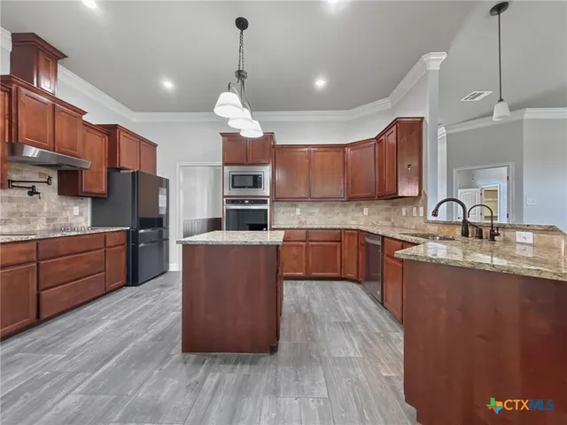 a kitchen with stainless steel appliances wooden floors wooden cabinets a refrigerator a sink a stove a microwave and cabinets