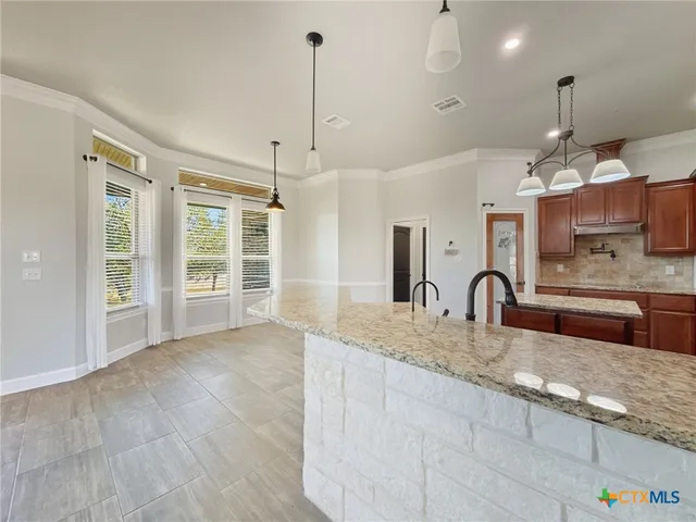 a kitchen with kitchen island granite countertop a sink a center island and stainless steel appliances