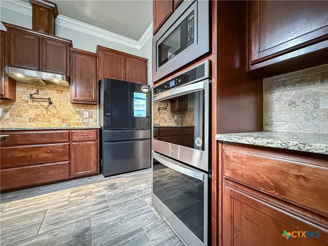 a kitchen with granite countertop stainless steel appliances and wooden cabinets