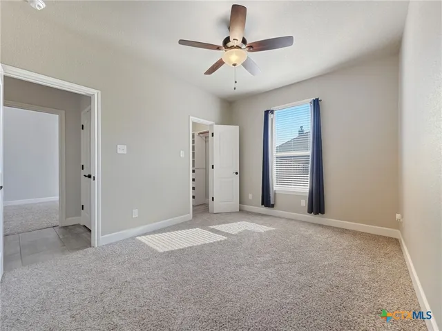 an empty room with closet and a ceiling fan