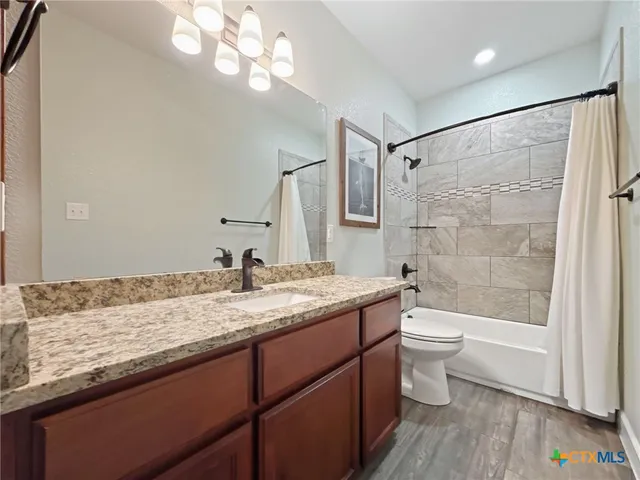 a bathroom with a granite countertop sink a toilet and bathtub