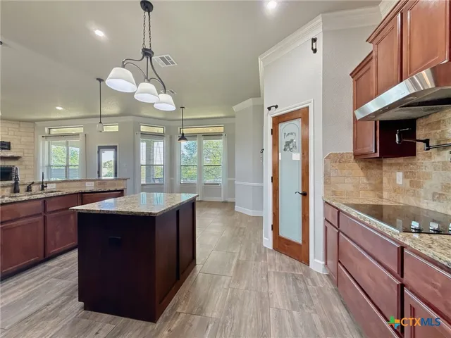 a large kitchen with stainless steel appliances granite countertop a sink and wooden floor