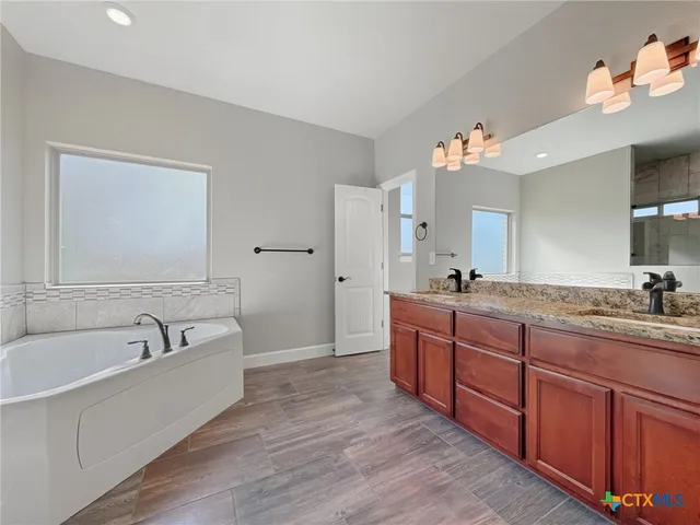 a spacious bathroom with a granite countertop tub sink and mirror