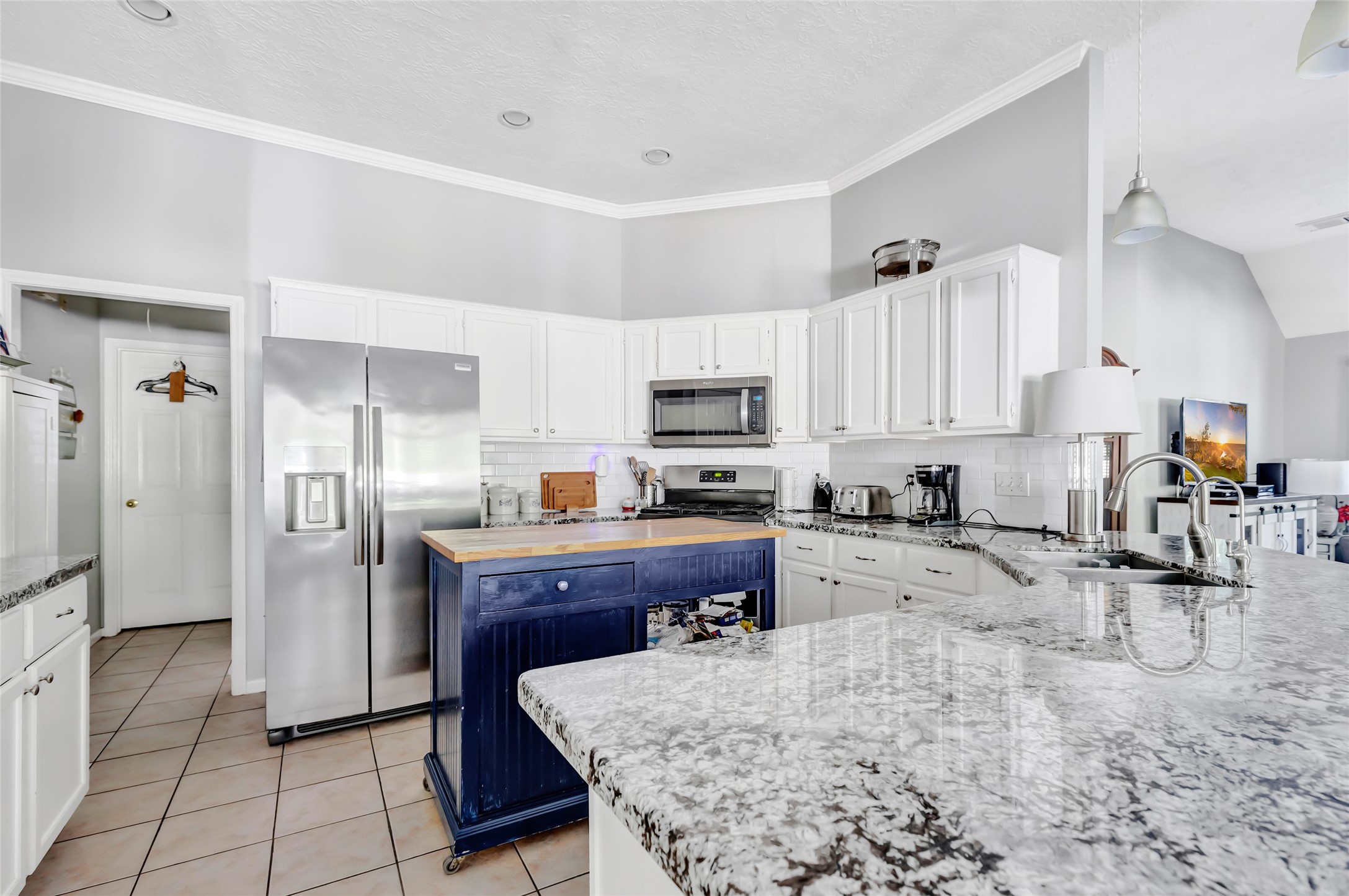 1014 North Rivershire Drive Conroe, TX 77304 - Photo 30 of 37 a kitchen with granite countertop a refrigerator a stove a sink a counter space and cabinets