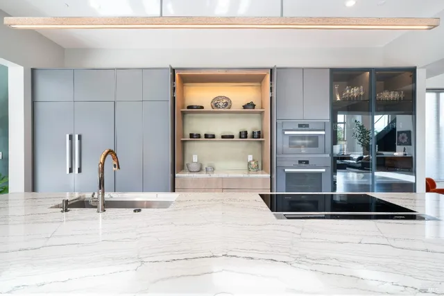 a view of a kitchen with kitchen island a large counter top space a sink stainless steel appliances and windows