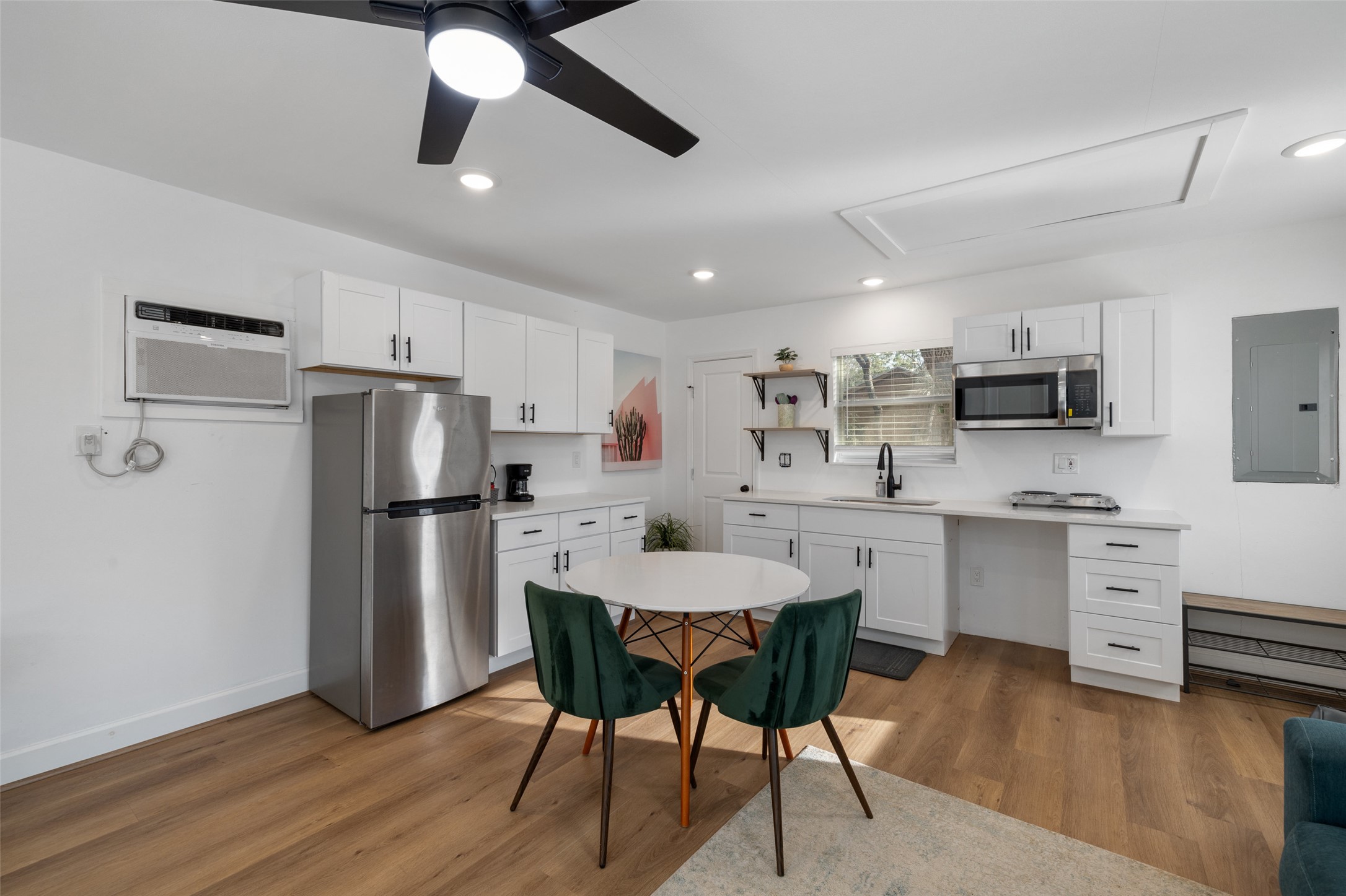 5519 Hiline Road Austin, TX 78734 - Photo 29 of 40 Kitchen featuring stainless steel appliances, a sink, white cabinetry, electric panel, and a wall mounted air conditioner