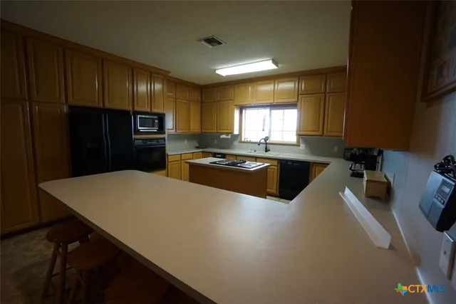 a kitchen with kitchen island a sink dishwasher a refrigerator and a stove with wooden floor