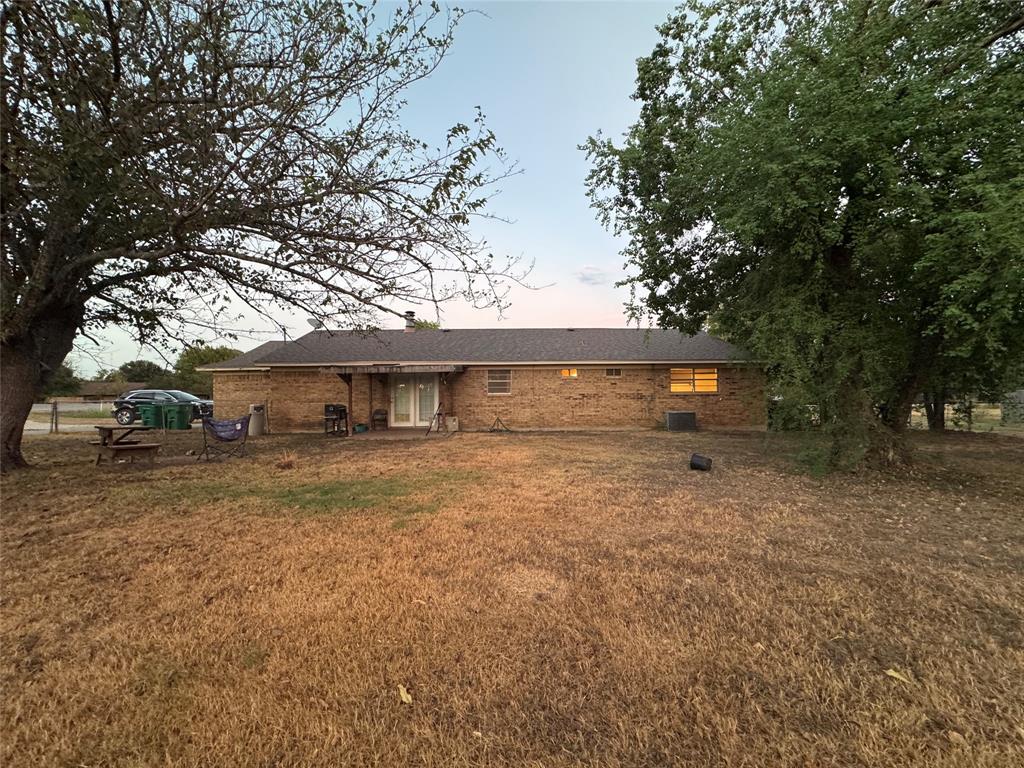 721 Mackey Ranch Road Bruceville-Eddy, TX 76524 - Photo 28 of 33 Brick exterior with a dark-shingle roof, double patio doors, and mature trees